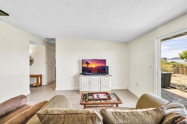 living area featuring a textured ceiling, baseboards, and light tile patterned floors