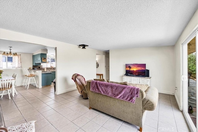 living area featuring a wealth of natural light, light tile patterned floors, baseboards, and a textured ceiling
