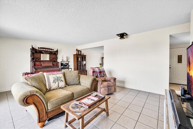 living room with a textured ceiling, baseboards, and light tile patterned floors