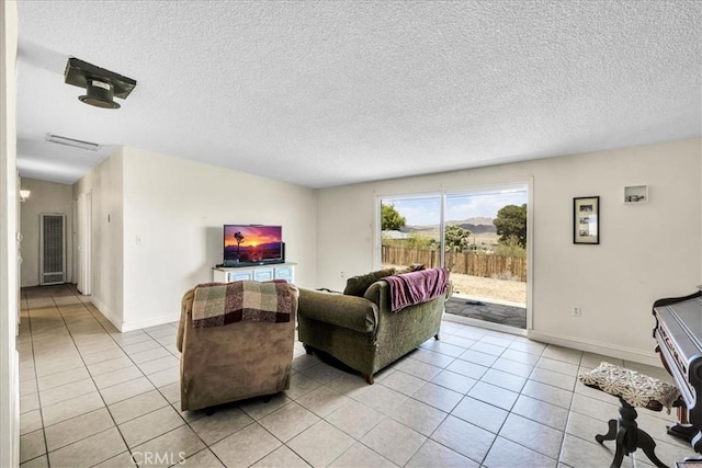 living room with light tile patterned floors, baseboards, and a textured ceiling