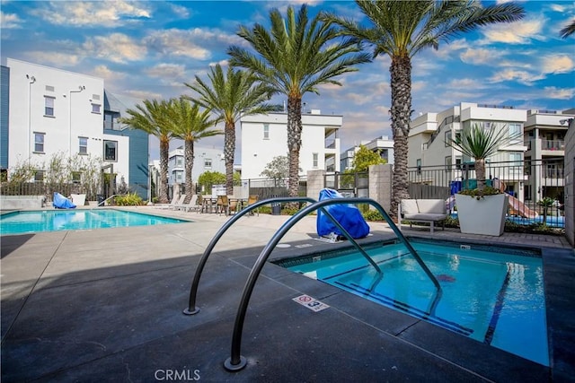 community pool featuring a patio, a residential view, and fence