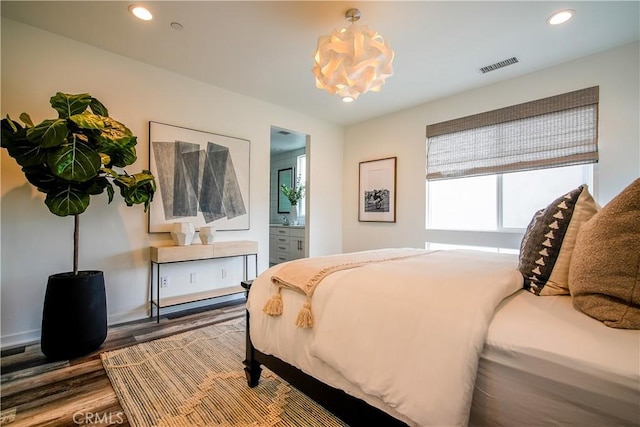 bedroom featuring wood finished floors, ensuite bath, visible vents, recessed lighting, and a notable chandelier