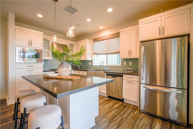 kitchen featuring a kitchen breakfast bar, dark wood finished floors, a kitchen island, and appliances with stainless steel finishes