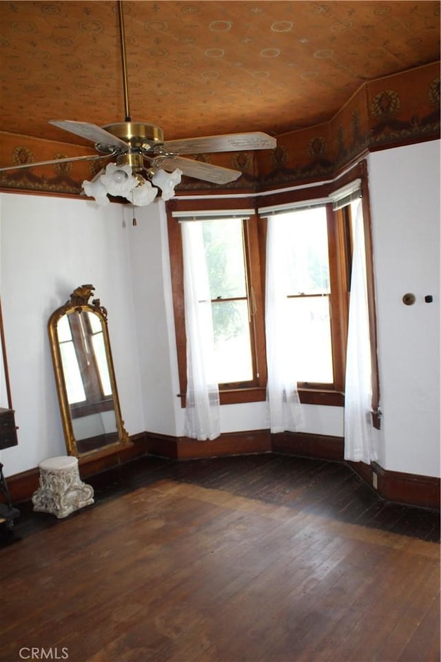 interior space with baseboards, a ceiling fan, and dark wood-style floors