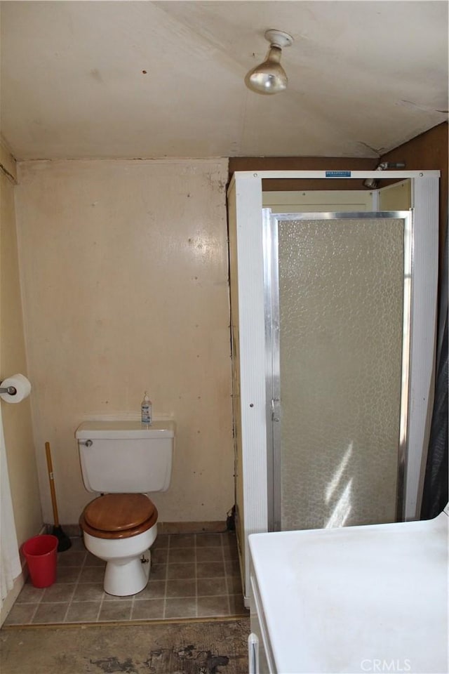 full bathroom with a stall shower, tile patterned flooring, baseboards, and toilet