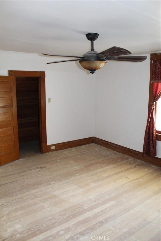 spare room with ceiling fan, light wood-style flooring, and baseboards
