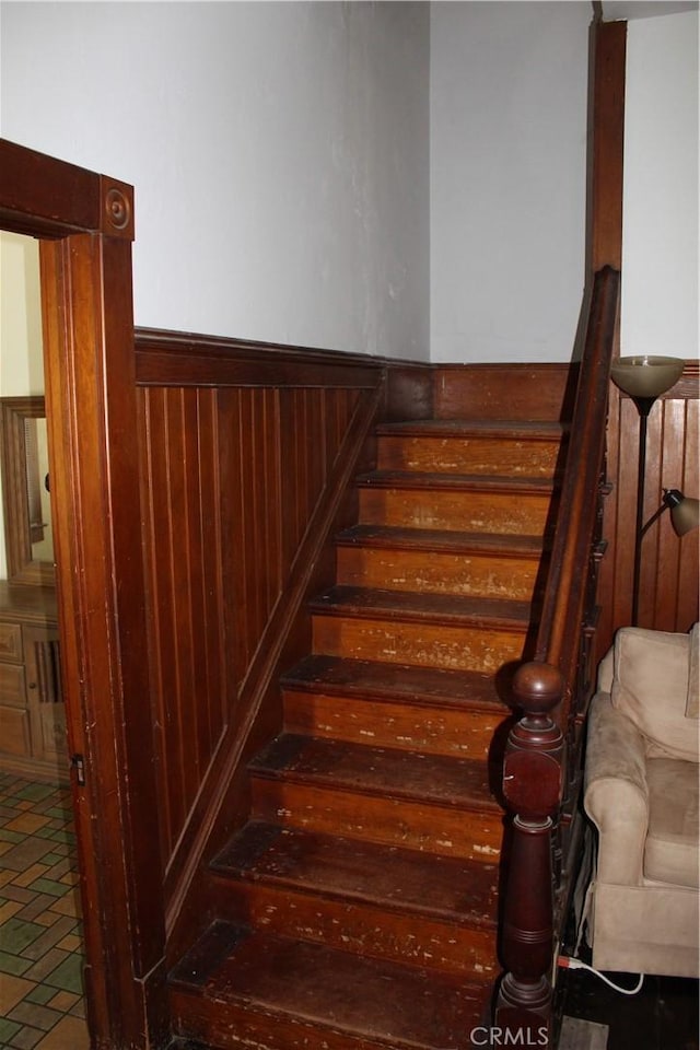 stairs with a wainscoted wall and wooden walls
