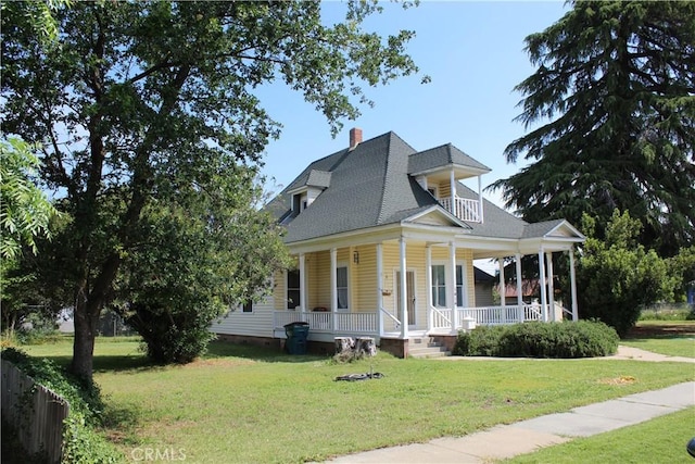 country-style home with a porch, roof with shingles, a front lawn, and a chimney