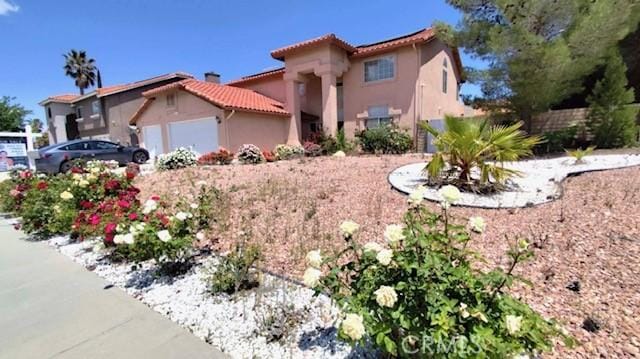 view of front of house with stucco siding, a tiled roof, and an attached garage