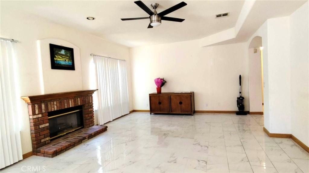 unfurnished living room featuring visible vents, baseboards, ceiling fan, arched walkways, and marble finish floor