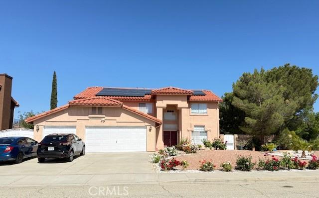 41854 Cabo Ct, Palmdale, CA 93551 - mediterranean / spanish house featuring an attached garage, stucco siding, roof mounted solar panels, driveway, and a tiled roof