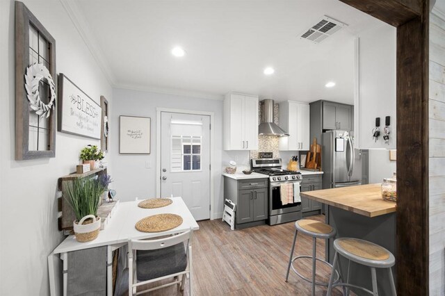 586 Del Mar Ave, Chula Vista, CA 91910 - kitchen with stainless steel appliances, wall chimney range hood, crown molding, light wood finished floors, and a breakfast bar area