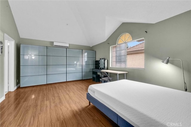 bedroom with lofted ceiling, a wall mounted AC, and wood finished floors