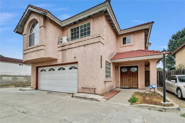 view of front facade with stucco siding, a tiled roof, an attached garage, and fence