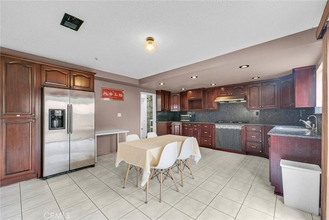 kitchen with a sink, decorative backsplash, stainless steel fridge, and light tile patterned floors