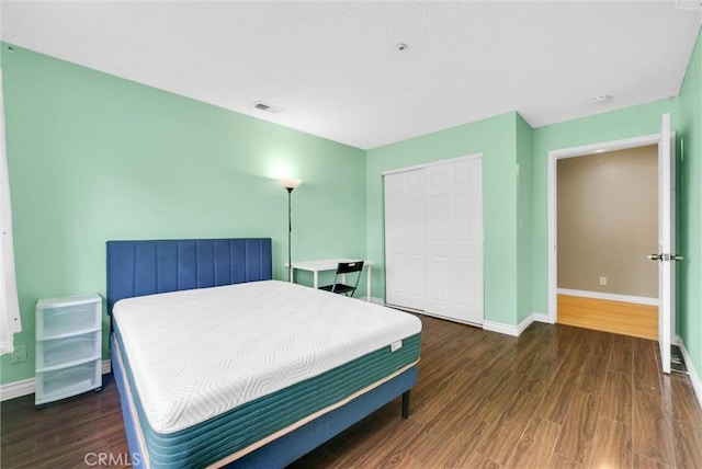 bedroom with baseboards, a closet, visible vents, and wood finished floors