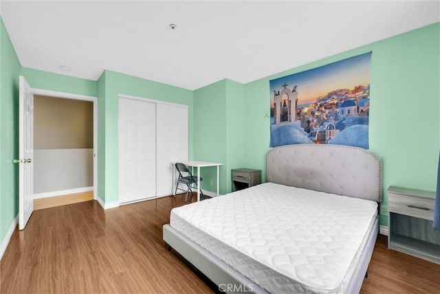 bedroom with baseboards, a closet, and wood finished floors