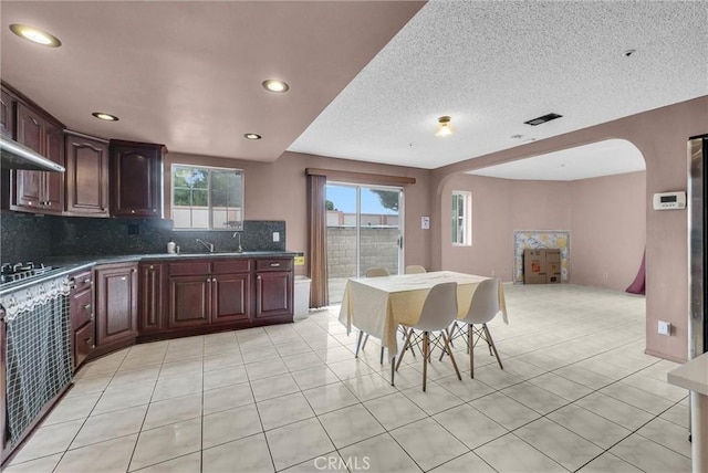 kitchen with light tile patterned floors, tasteful backsplash, arched walkways, and recessed lighting