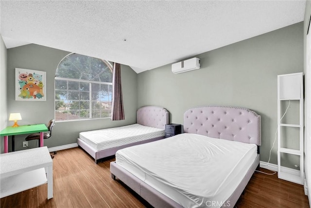 bedroom with vaulted ceiling, a wall mounted air conditioner, baseboards, and wood finished floors