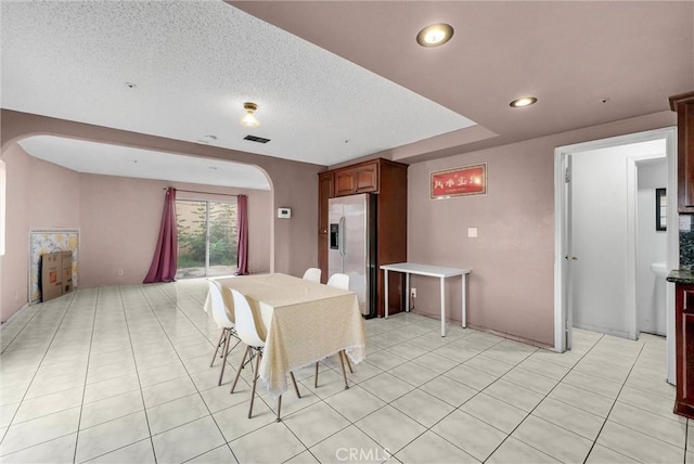 dining area with a textured ceiling, visible vents, arched walkways, light tile patterned flooring, and recessed lighting