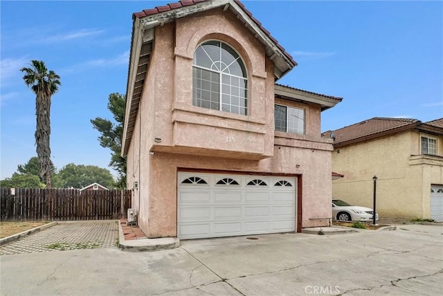 traditional home with an attached garage, a tiled roof, stucco siding, and concrete driveway