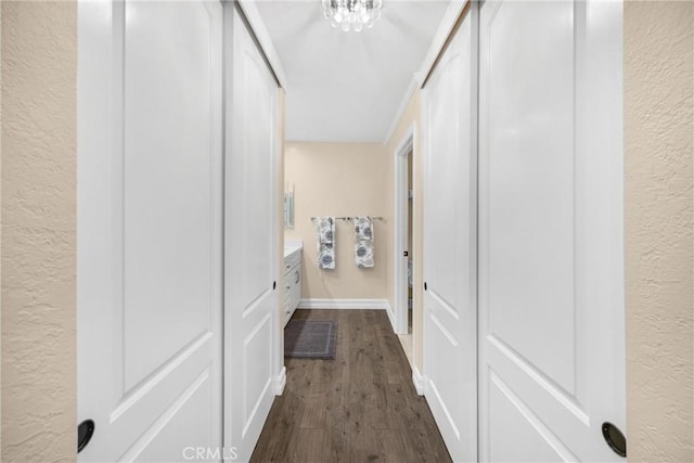 hall featuring baseboards, dark wood-style floors, and a textured wall