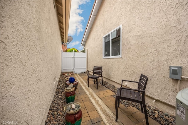 view of side of home featuring a patio, stucco siding, and fence