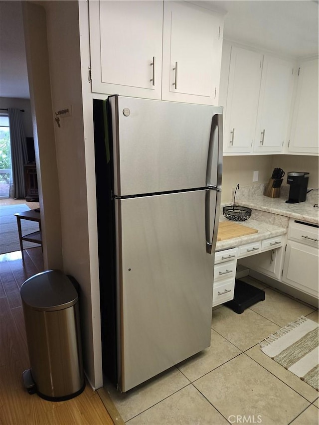 185 Avenida Majorca Unit A, Laguna Woods, CA 92637 - kitchen with freestanding refrigerator, white cabinets, light tile patterned flooring, and light stone counters