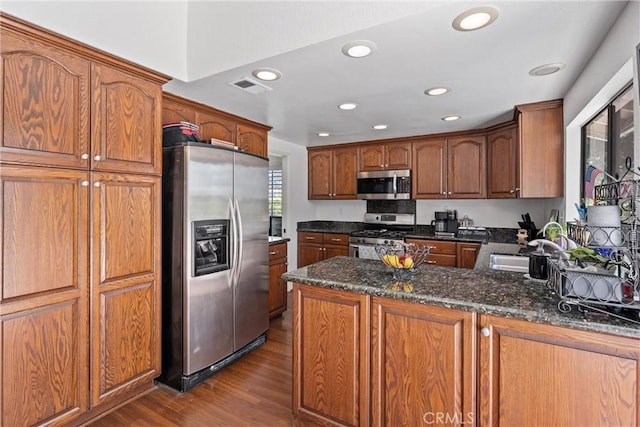 2757 Cape Dr, Corona, CA 92882 - kitchen featuring stainless steel appliances, dark wood finished floors, dark stone counters, a peninsula, and brown cabinets
