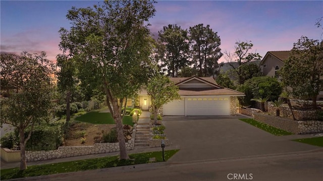 2757 Cape Dr, Corona, CA 92882 - obstructed view of property featuring driveway, an attached garage, a tile roof, stairway, and stone siding