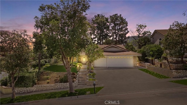 2757 Cape Dr, Corona, CA 92882 - obstructed view of property featuring concrete driveway, an attached garage, a tile roof, stairway, and stone siding