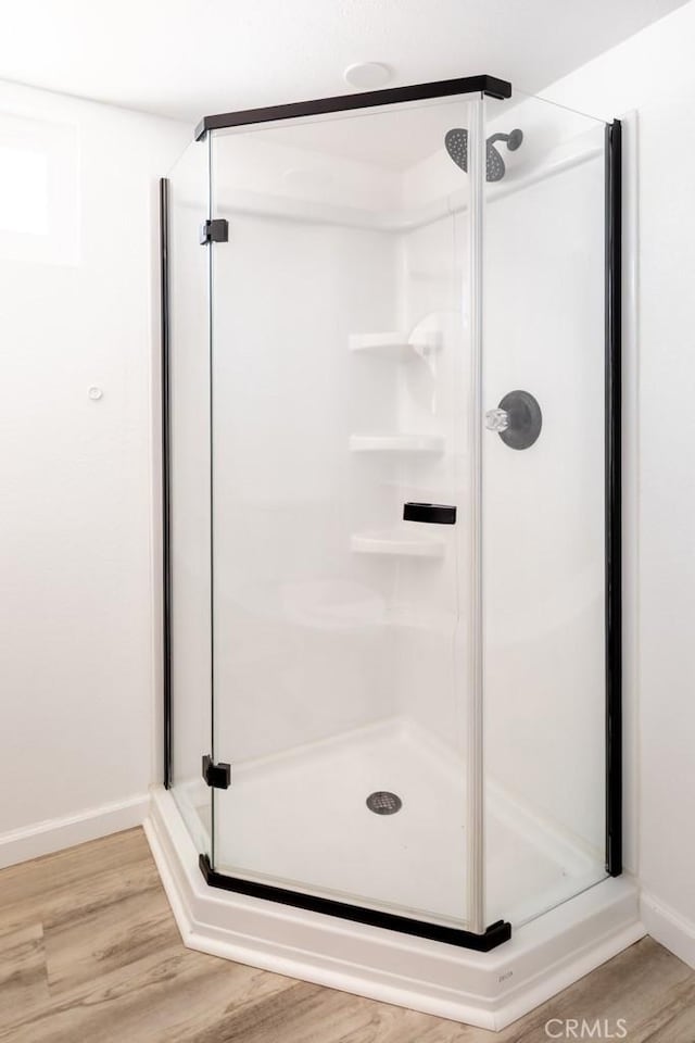 full bath featuring baseboards, wood finished floors, and a shower stall