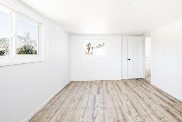 empty room with baseboards, plenty of natural light, and wood finished floors