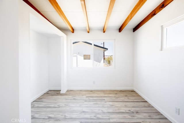 empty room featuring light wood-style flooring, baseboards, and beam ceiling