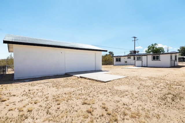 rear view of house with an outdoor structure, a garage, and fence