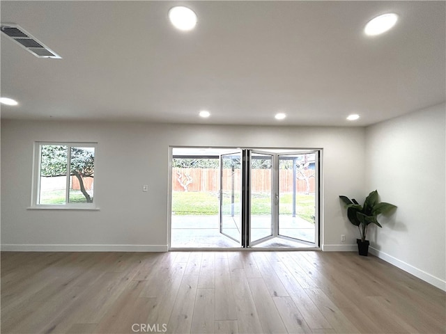 empty room with baseboards, wood finished floors, and recessed lighting