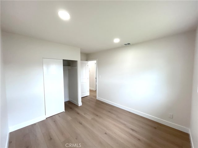 unfurnished bedroom with baseboards, light wood-style floors, a closet, and recessed lighting