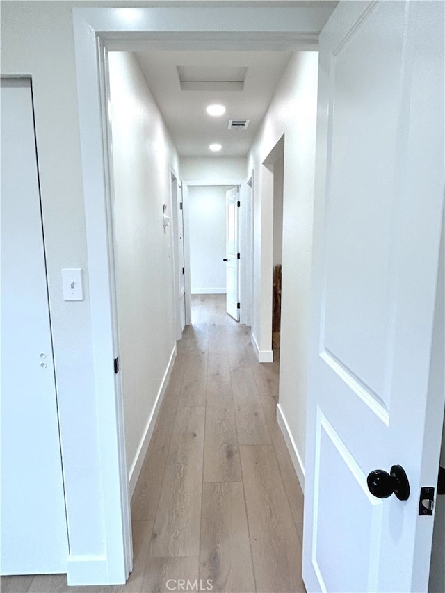 corridor with light wood-style floors and baseboards