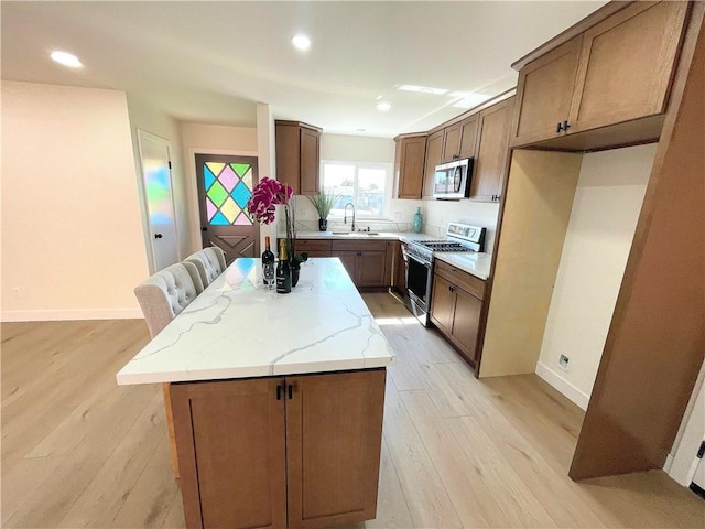 kitchen featuring appliances with stainless steel finishes, a center island, light wood-type flooring, a sink, and recessed lighting