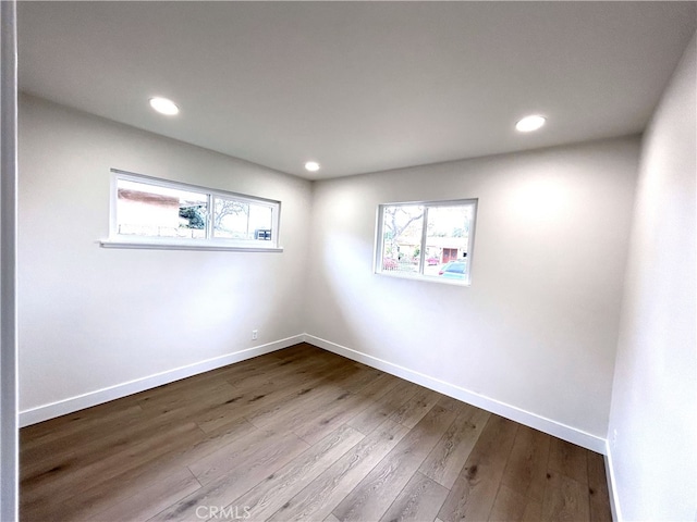 spare room featuring plenty of natural light, baseboards, dark wood-type flooring, and recessed lighting