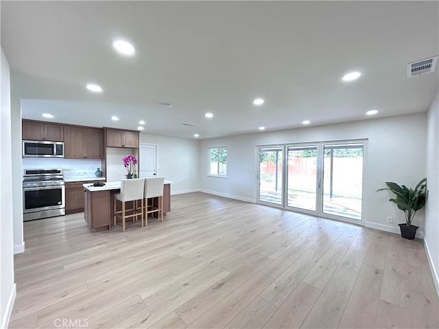kitchen featuring appliances with stainless steel finishes, open floor plan, baseboards, recessed lighting, and light wood finished floors