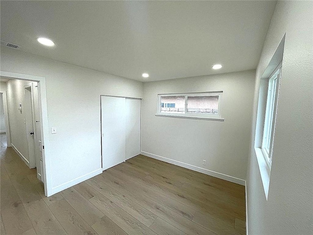 unfurnished bedroom featuring wood finished floors, recessed lighting, a closet, and baseboards