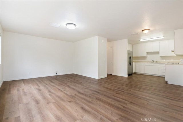 unfurnished living room featuring baseboards, a sink, and wood finished floors