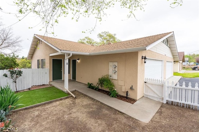 view of front of property with stucco siding, fence, and a gate