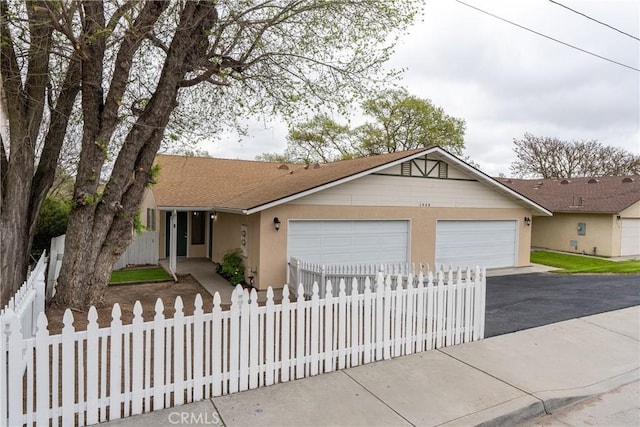 view of front facade with a garage, stucco siding, aphalt driveway, a shingled roof, and a fenced front yard