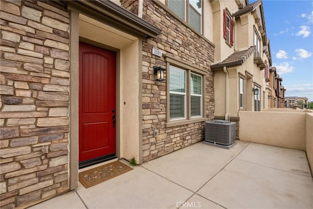 3981 E Huntington St, Ontario, CA 91761 - property entrance with stone siding, stucco siding, central AC unit, and a patio
