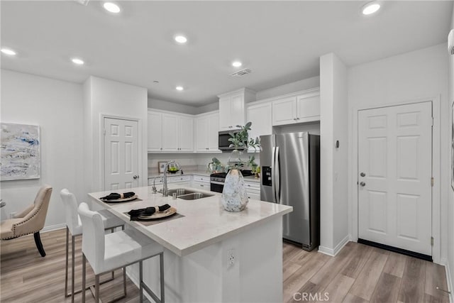 3981 E Huntington St, Ontario, CA 91761 - kitchen featuring a sink, light wood-style floors, stainless steel appliances, white cabinets, and an island with sink