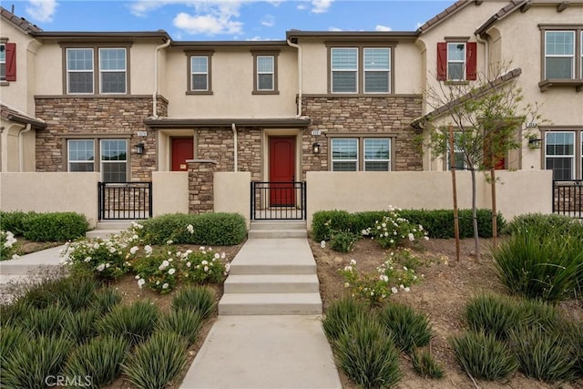 3981 E Huntington St, Ontario, CA 91761 - townhome / multi-family property with a gate, stucco siding, stone siding, and a fenced front yard