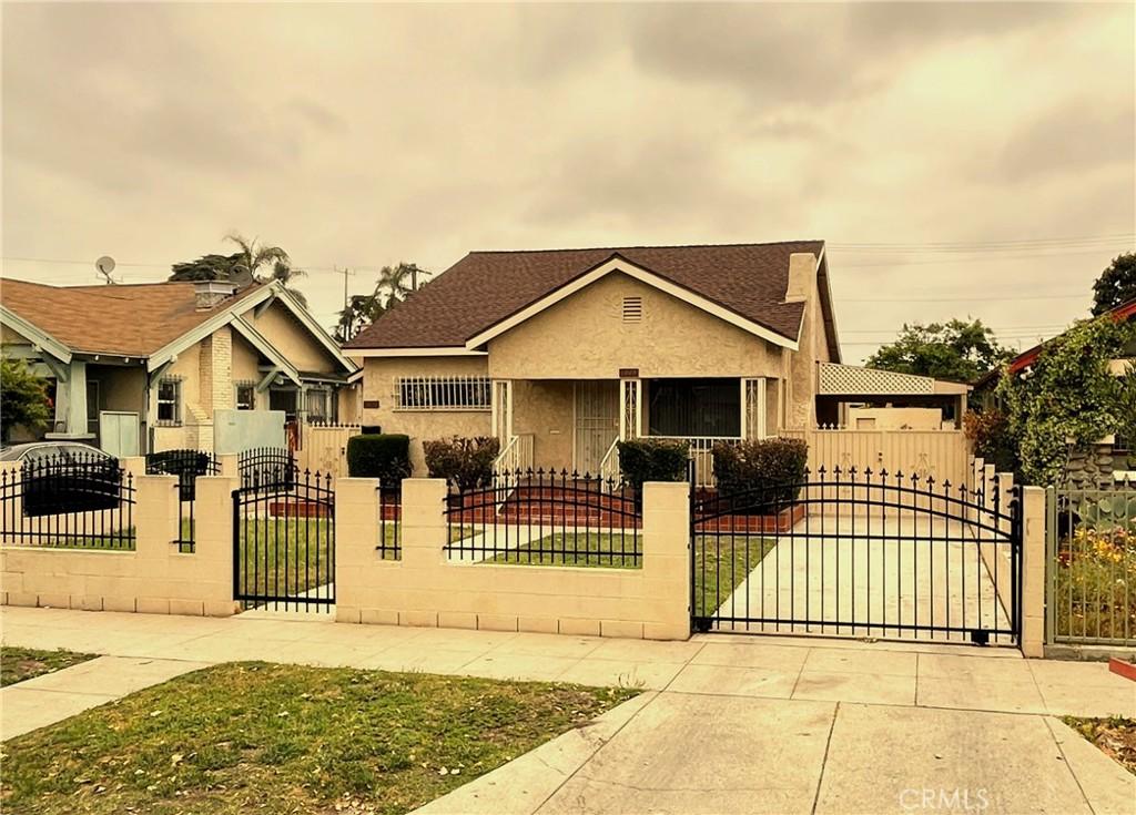bungalow-style house featuring a gate, a shingled roof, stucco siding, and a fenced front yard