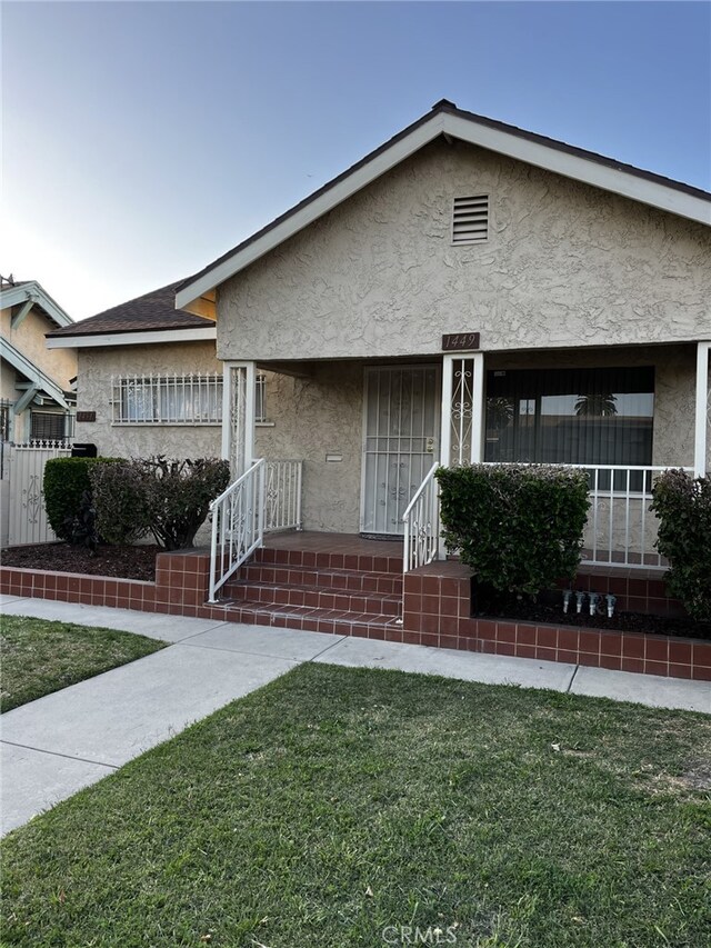 1449 W 45th St, Los Angeles, CA 90062 - bungalow-style home with stucco siding, a front lawn, and covered porch